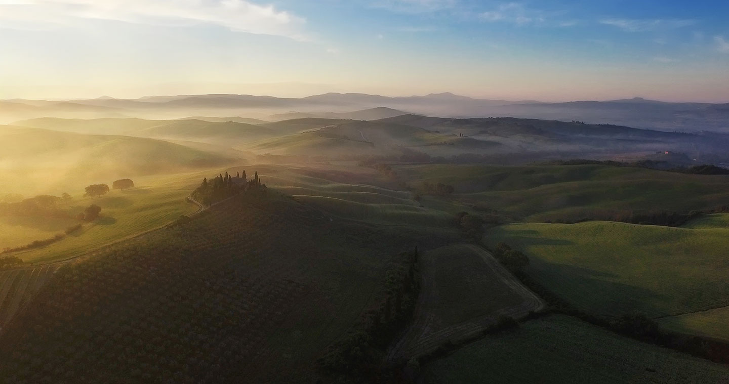 (Early morning light engulfs the rolling hills of Tuscany.)